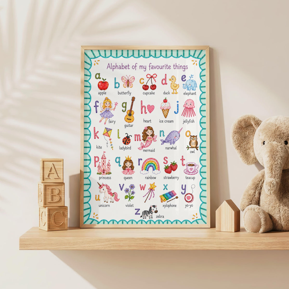 A framed alphabet poster rests on a wooden shelf next to wooden alphabet blocks, a small house-shaped block, and a plush elephant toy.