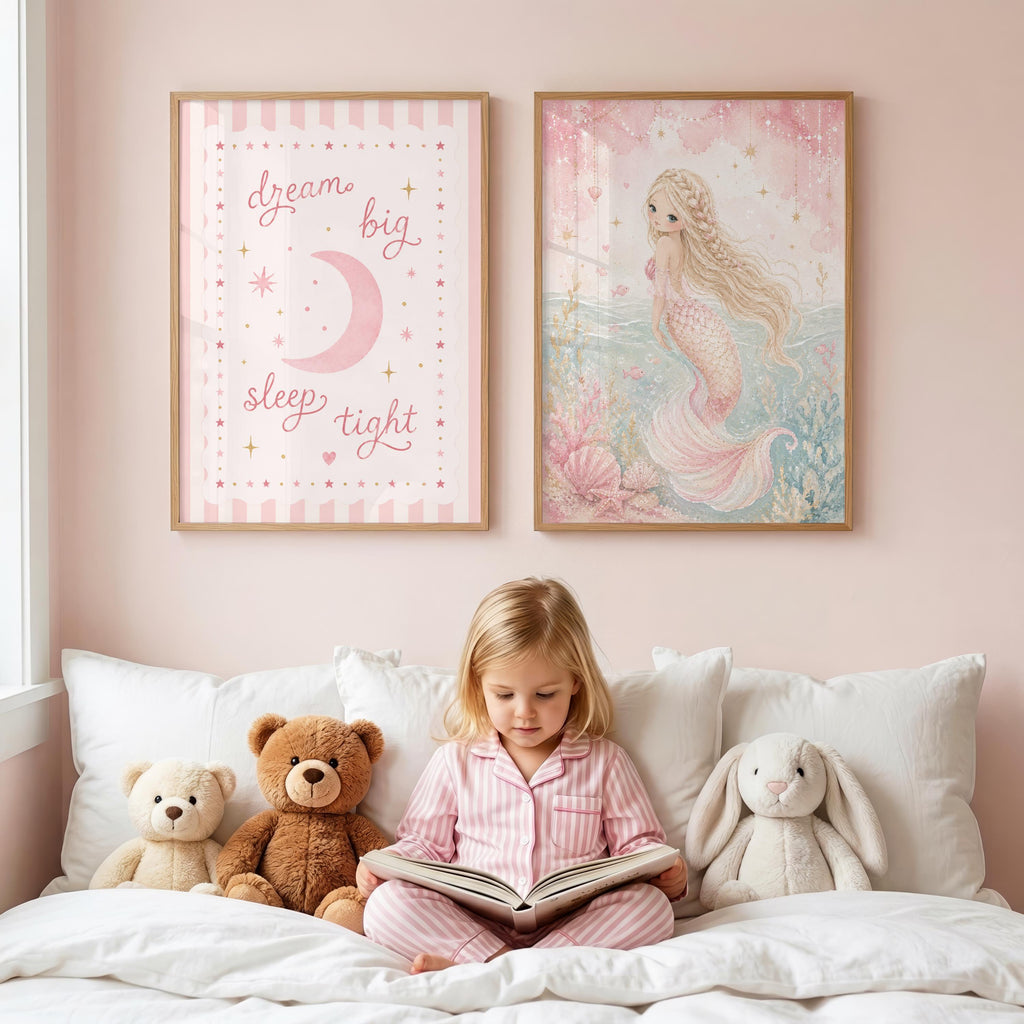 A young girl sits on a bed reading a book below two framed prints on a pink wall, flanked by stuffed bears and a rabbit.