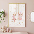A framed watercolor print in a pink room shows two monkeys wearing striped shirts and party hats on swings, surrounded by stars.