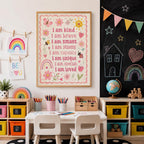 Pink children’s affirmation wall print displayed in a light wood frame above a kids’ art desk, styled in a colourful playroom or homeschool space with pencils, storage boxes, children’s artwork, rainbow decor, chalkboard wall, toys and a globe.