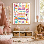 Framed affirmation print hanging on a nursery wall above a toy shelf, surrounded by pillows, a doll, and a wooden rocking horse.