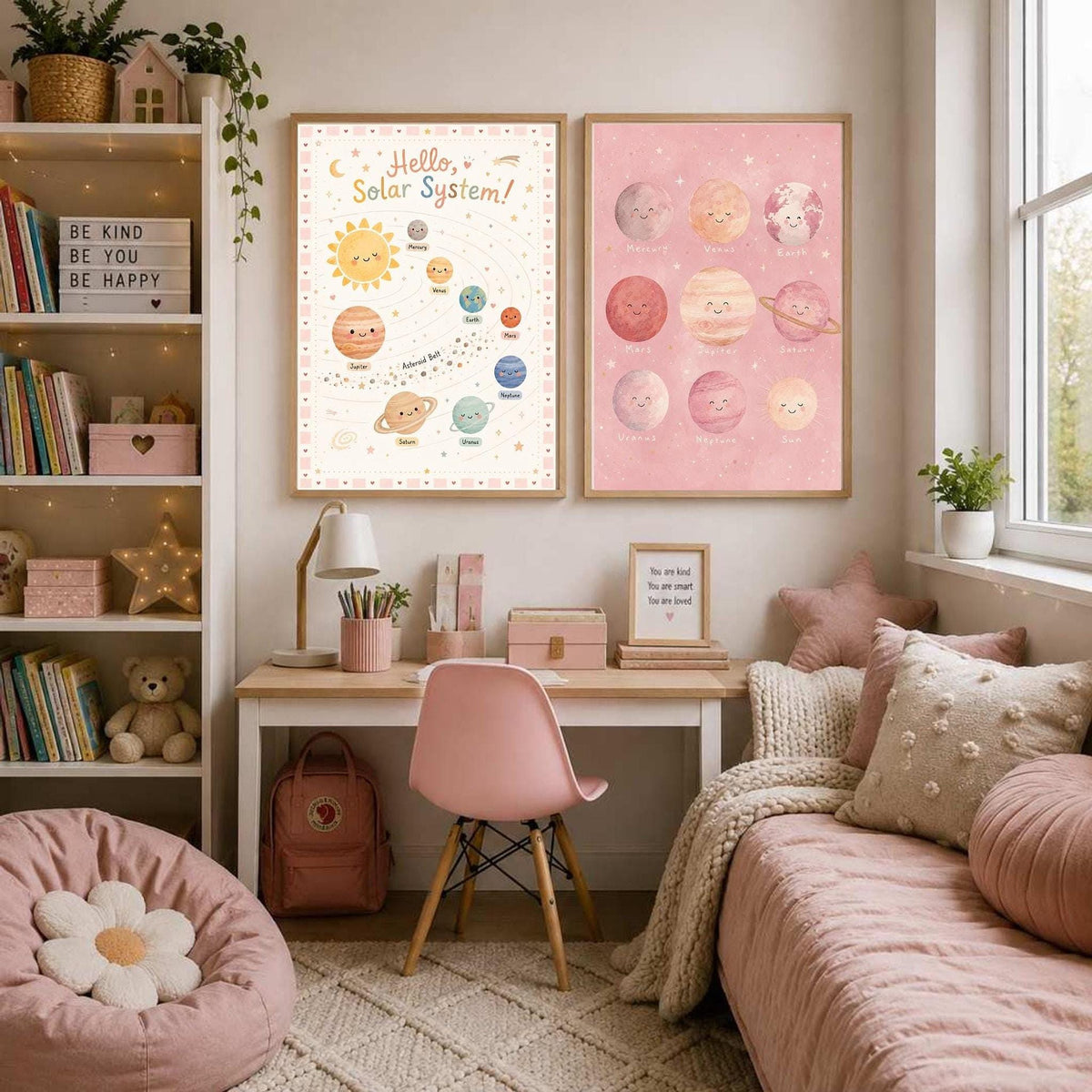 Two matching pink space art prints are displayed above a wooden desk next to a bookshelf and a bed.