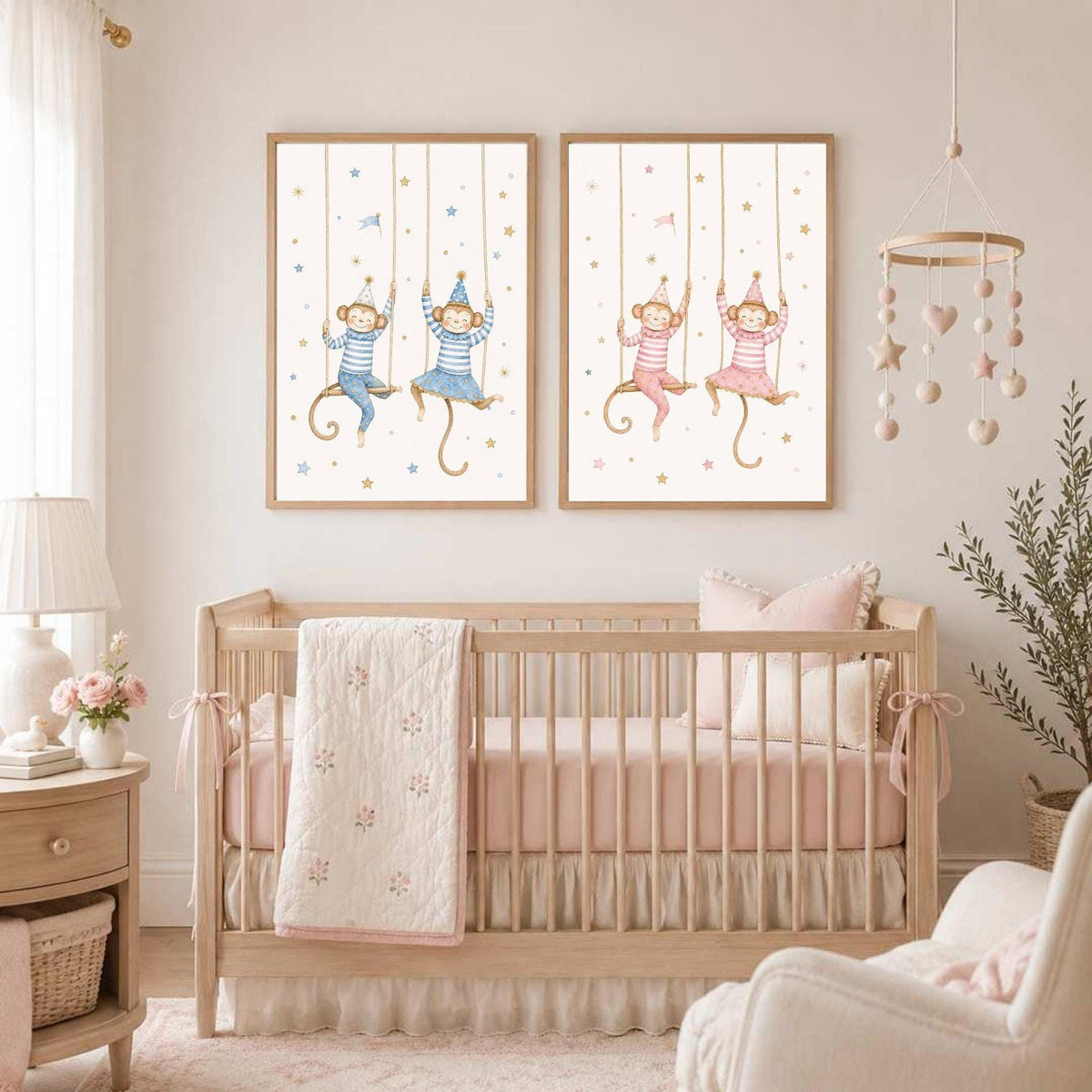 Two framed watercolor prints of monkeys on swings hang on a wall above a wooden baby crib.