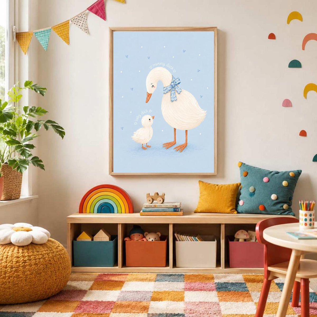 A framed duck print hangs above a low wooden cubby shelf filled with colorful storage bins and toys against a wall with multi-colored wall decals.