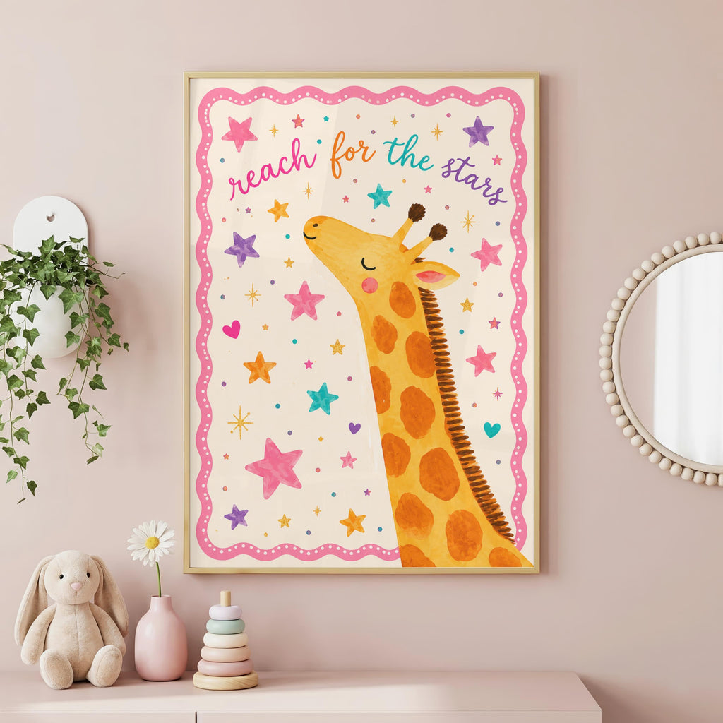 A framed children's print showing a giraffe looking up with the text reach for the stars against a pink star-patterned background, hanging on a pink wall near a white shelf with plants and a toy.