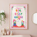 Framed wall art print of a goose wearing a pink hat with text reading Dream BIG be SILLY little GOOSE hanging on a pink wall.