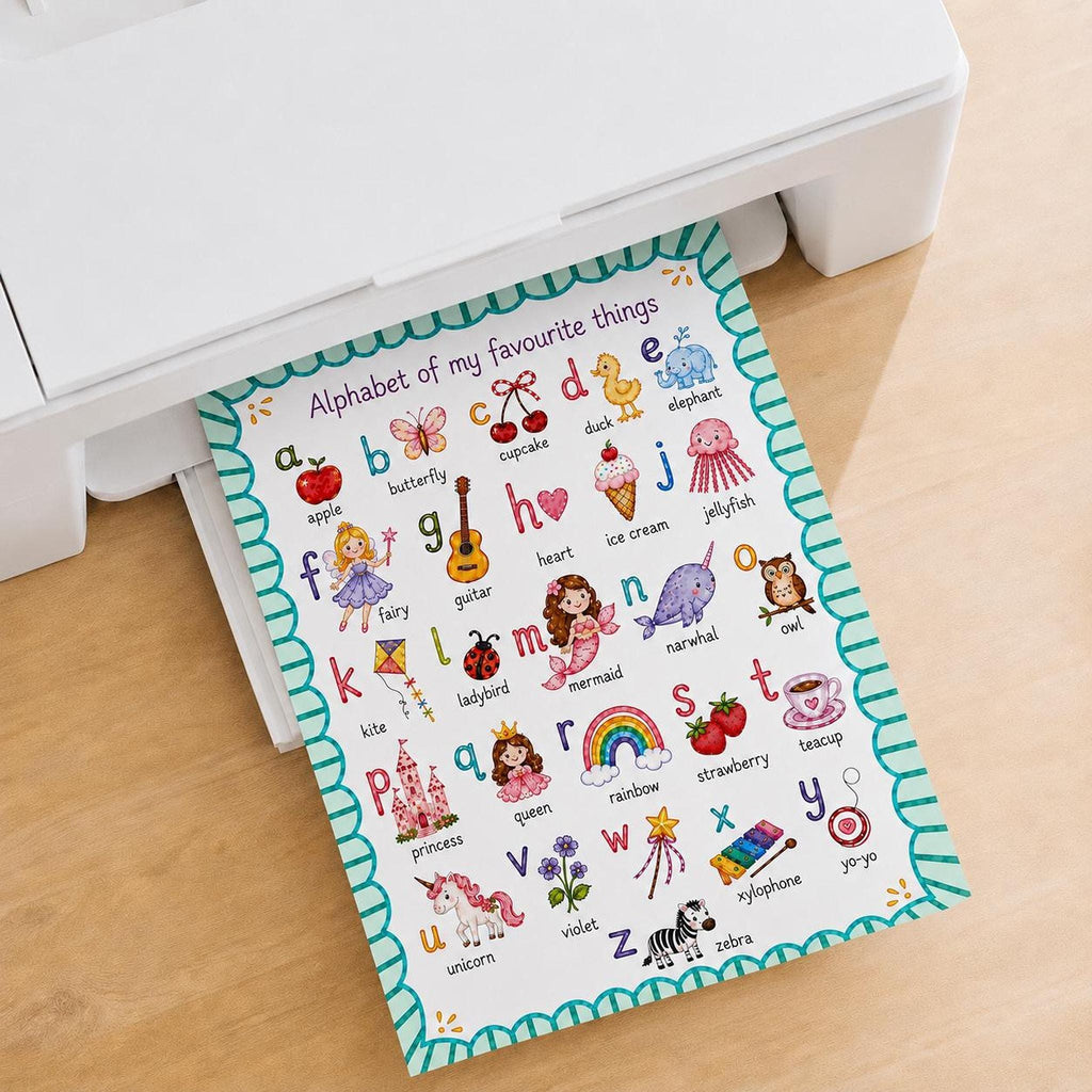 An alphabet poster emerges from the paper tray of a white printer resting on a wooden surface.
