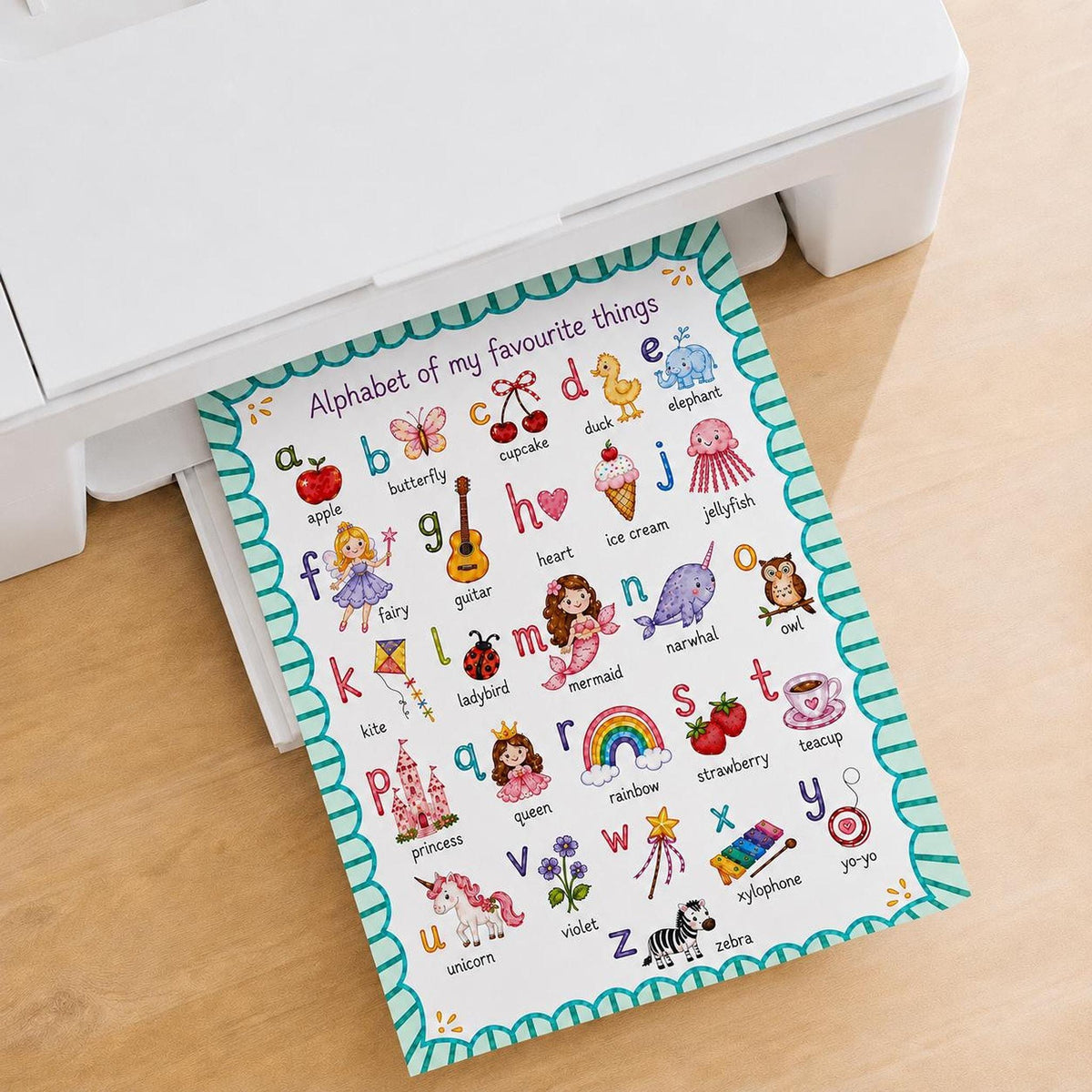 An alphabet poster emerges from the paper tray of a white printer resting on a wooden surface.
