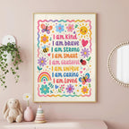 A framed children's affirmation poster hangs on a pink wall above a shelf with a stuffed bunny, a flower vase, and a stacking toy.