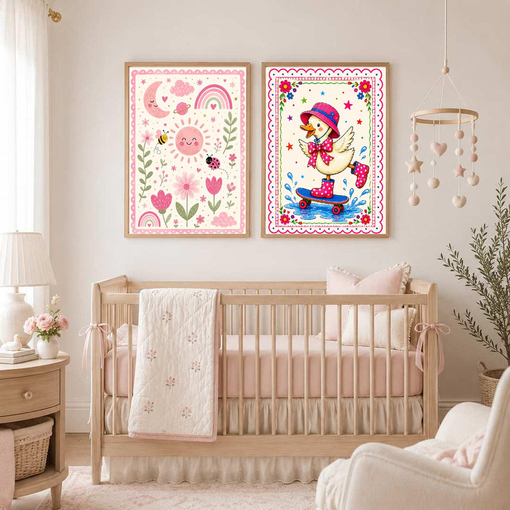 Two framed art prints hanging above a baby crib, with the left print showing a pink nature scene with a sun and flowers, and the right print showing the skateboarding duck.