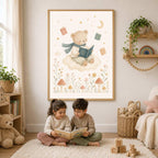 Two children sit on a rug reading a book beneath a framed watercolor print of a teddy bear on a cloud.