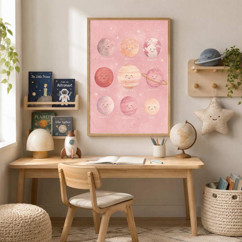 A framed pink solar system poster hangs above a wooden desk set with a globe, lamp, and books in a child's room.