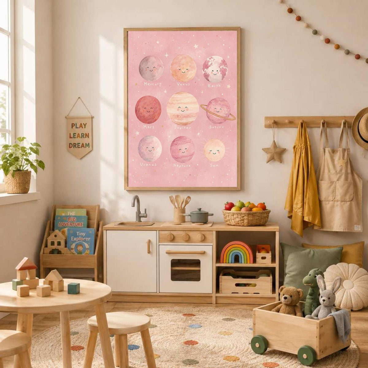 A pink planet print hangs over a child's play kitchen and activity table filled with toys.