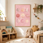 The framed pink planet art is displayed on a wall next to low wooden toy shelves and a stuffed animal.
