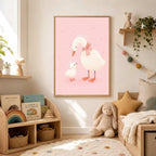 Framed pink duck family art hanging on a white wall above a wooden shelving unit filled with books and toys in a nursery.