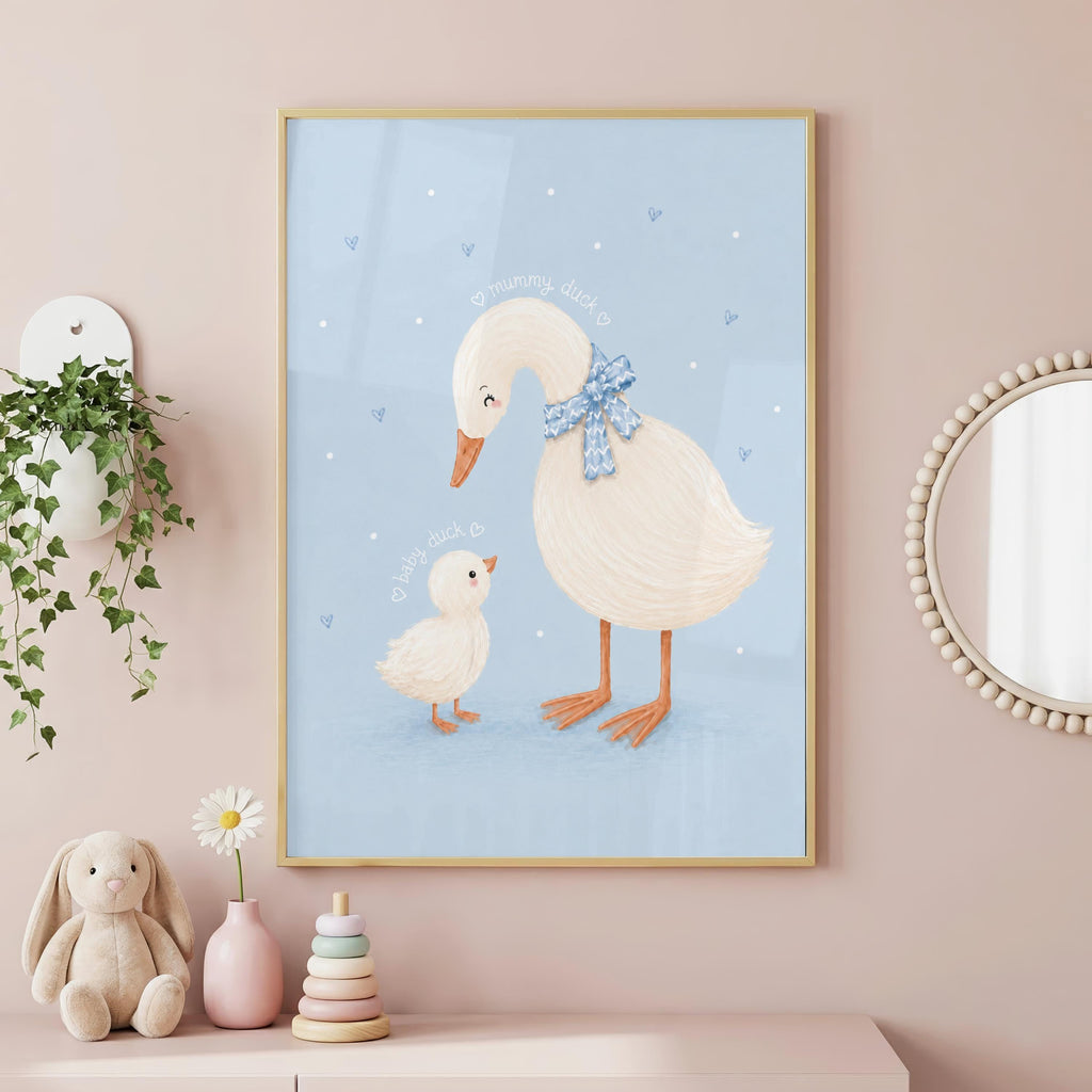 A framed illustration of a mother and baby duck on a light blue background hangs on a pink wall above a dresser with toys and a plant.