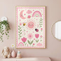 A framed pink whimsical poster with floral, sun, moon, and rainbow illustrations hangs on a pink wall above a children's bedroom table.