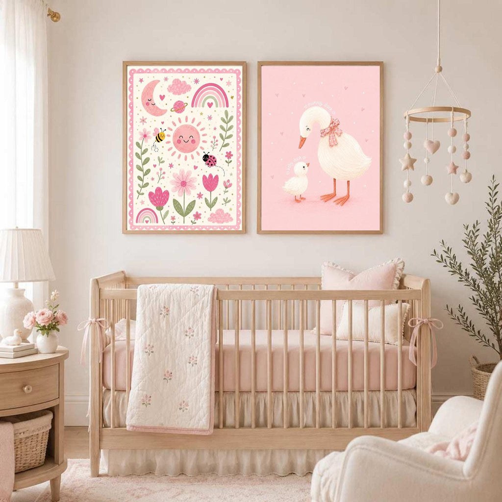Two framed posters featuring a pink whimsical nature print and a mother duck with a duckling hang above a wooden baby crib.