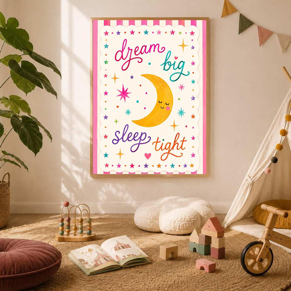 A framed wall art poster displaying a cute crescent moon illustration and dream big sleep tight lettering is mounted on a white wall next to a teepee and wooden toy blocks.