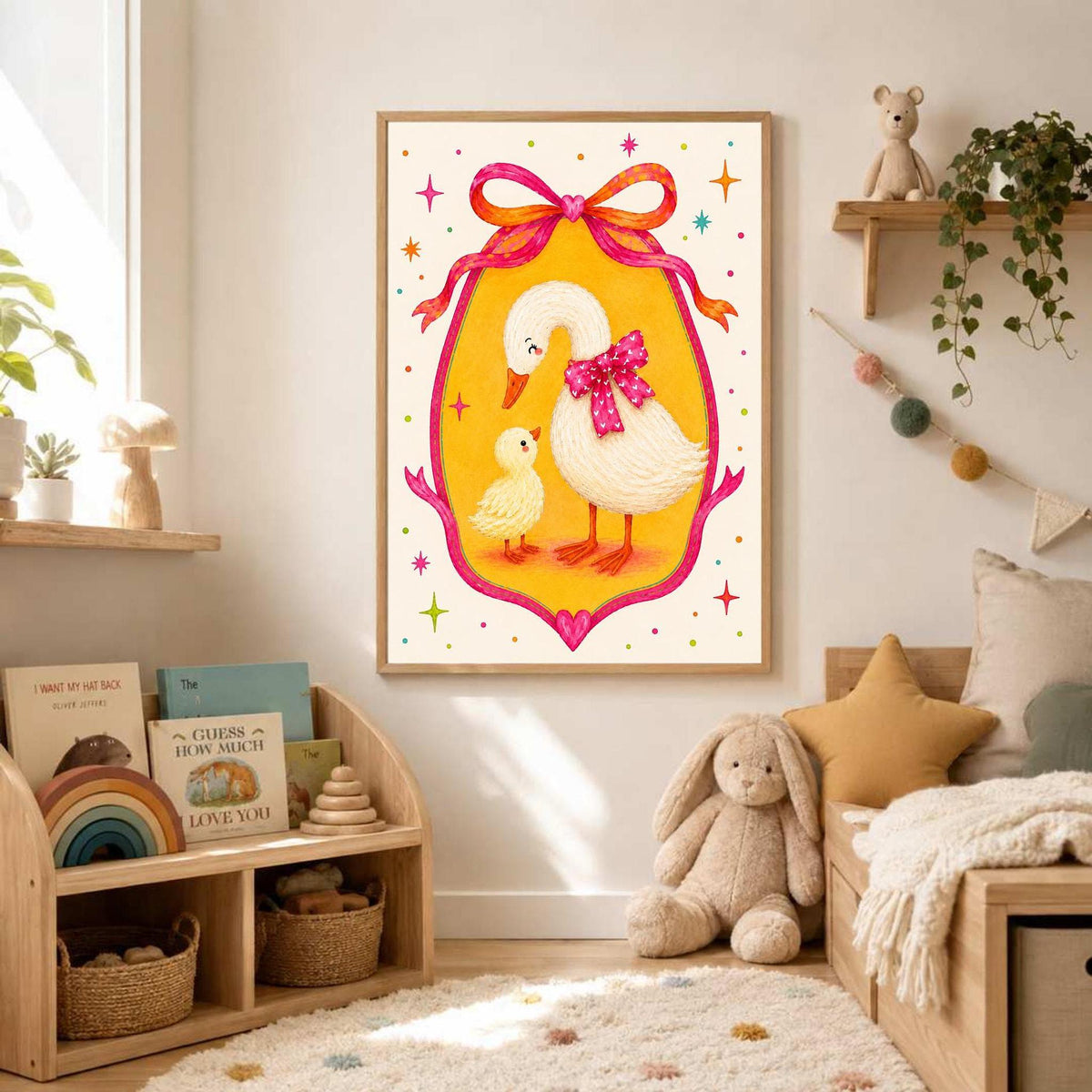 A framed goose and duckling print hangs above a child's wooden shelving unit and a bed filled with pillows and a stuffed animal in a brightly lit room.