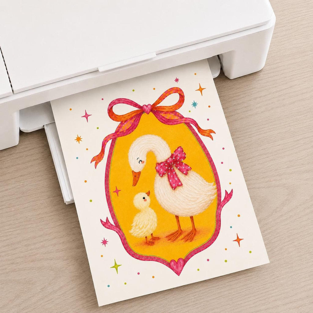 A white home printer rests on a wooden desk, printing out a whimsical illustration of a mother goose with a pink bow and her yellow duckling.