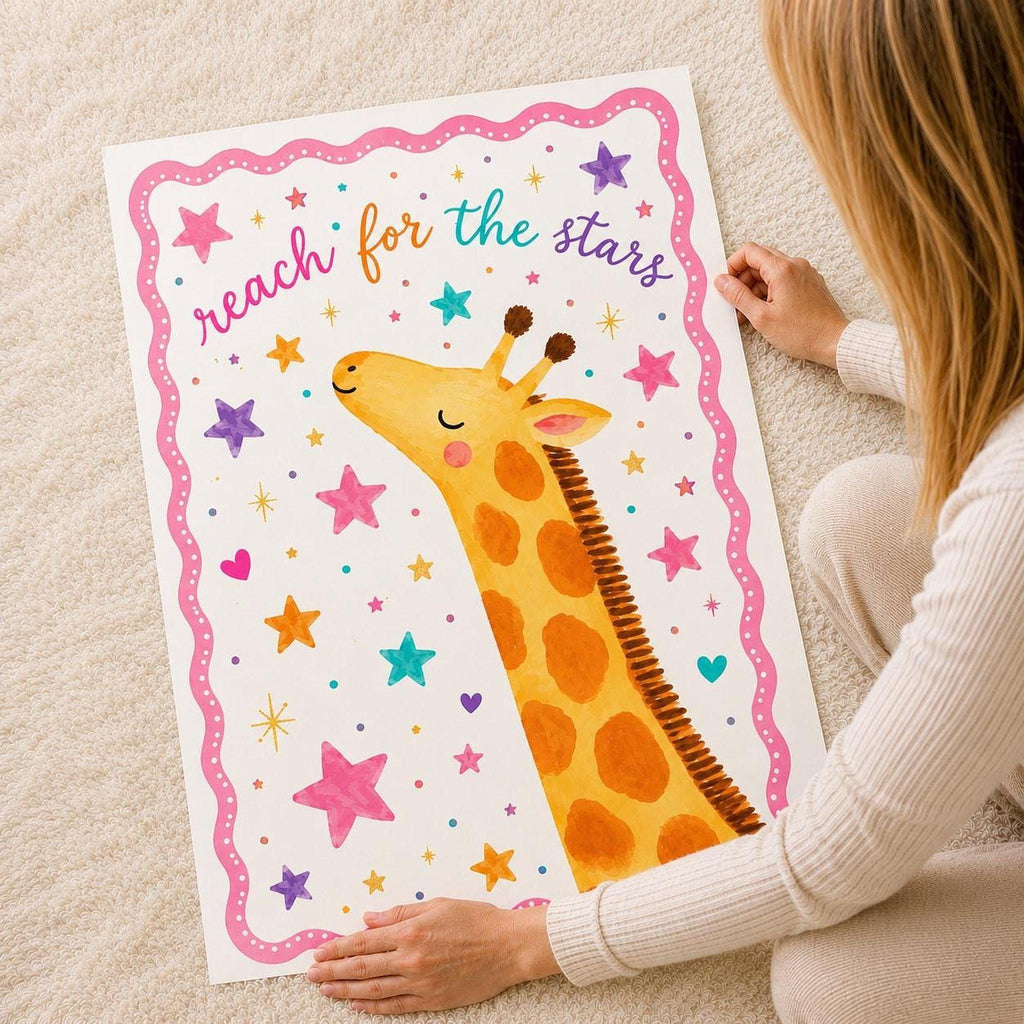 A person sitting on a carpet holds up a large vertical print of an illustrated giraffe surrounded by stars and the text reach for the stars.
