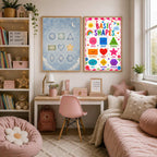A study desk area features two framed posters on the wall above, surrounded by bookshelves and a pink daybed.