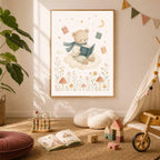 A framed print of a bear reading on a cloud is hung on a neutral wall in a playroom with wooden toys and an open book on the rug.
