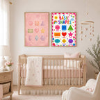 Two shapes posters hang side by side centered above a wooden baby crib in a softly lit nursery.