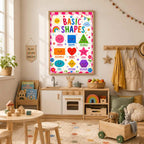 A framed basic shapes educational poster hangs on a playroom wall above a toy kitchen set and wooden table.
