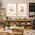 Two framed watercolor prints of a rabbit on a moon and a fairy on a mushroom displayed above a shelving unit.