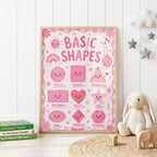 Pink educational shapes wall print featuring smiling circle, square, triangle, rectangle, heart, star, oval, diamond and hexagon shapes with a rainbow, flowers, clouds and playful pink details.