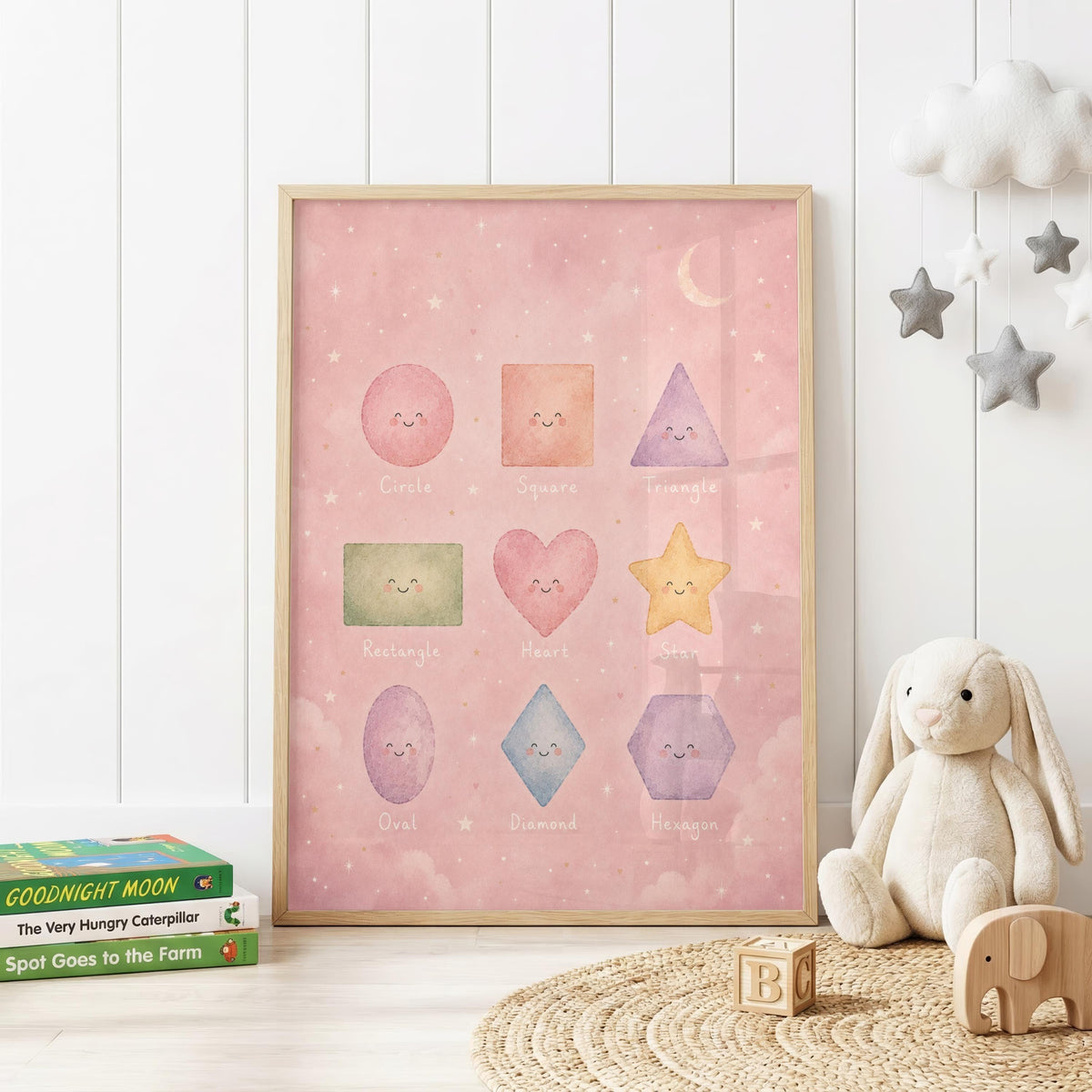 Pastel educational shapes nursery print featuring smiling circle, square, triangle, rectangle, heart, star, oval, diamond and hexagon shapes on a soft pink background with stars, clouds and a crescent moon.