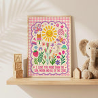 Colourful girls nursery wall print featuring the quote I love you more than the sun, moon and all of the stars, surrounded by smiling sun and moon illustrations, butterflies, flowers, hearts, rainbow and a pink gingham border.